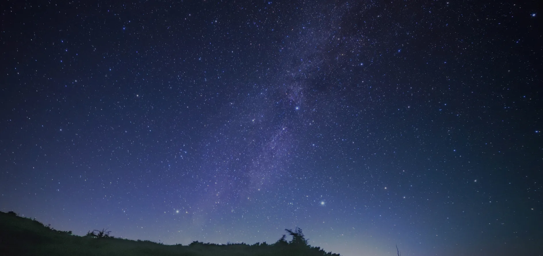 山々の上に広がる美しい星空が、夜空を彩る幻想的な風景