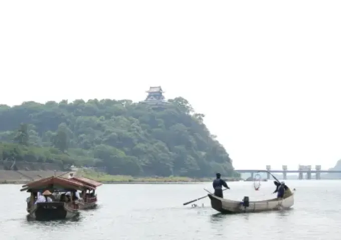 古都の川をゆく屋形船と、背景にそびえ立つ城